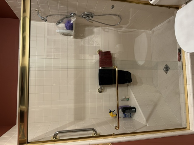 Frameless glass shower enclosure with marble tile